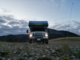 Motorhome no Alasca com os faróis acesos ao entardecer, estacionado na Dalton Highway