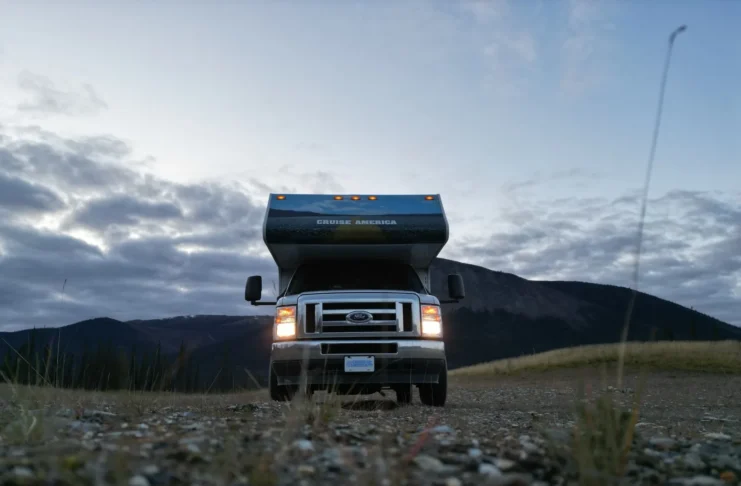 Motorhome no Alasca com os faróis acesos ao entardecer, estacionado na Dalton Highway